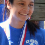 Lisette Lopez, staff writer, smiles for the camera after receiving her bronze medal at the cross country district meet.