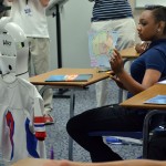 Freshman Micah Watson served as Storm Malone's robot buddy in Mr. Jeremy Cauley's Geography class for his first day back to school.  She holds a colored map up so that he can see it at home via the robot.  Malone returned to the class for the first time via a VGo Robot months after a domestic violence incident took his sister and mother's lives and left him with some brain damage. (Josaphine Xayyaraj photo)