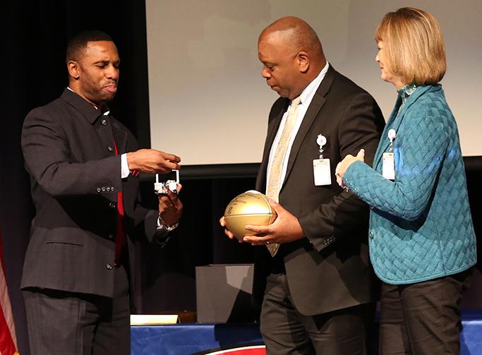 NFL Player Ray Crockett presents principal Carlos Meekins with a golden football from the NFL and lets him wear one of his Superbowl rings. (photo by: Cynthia Rangel)